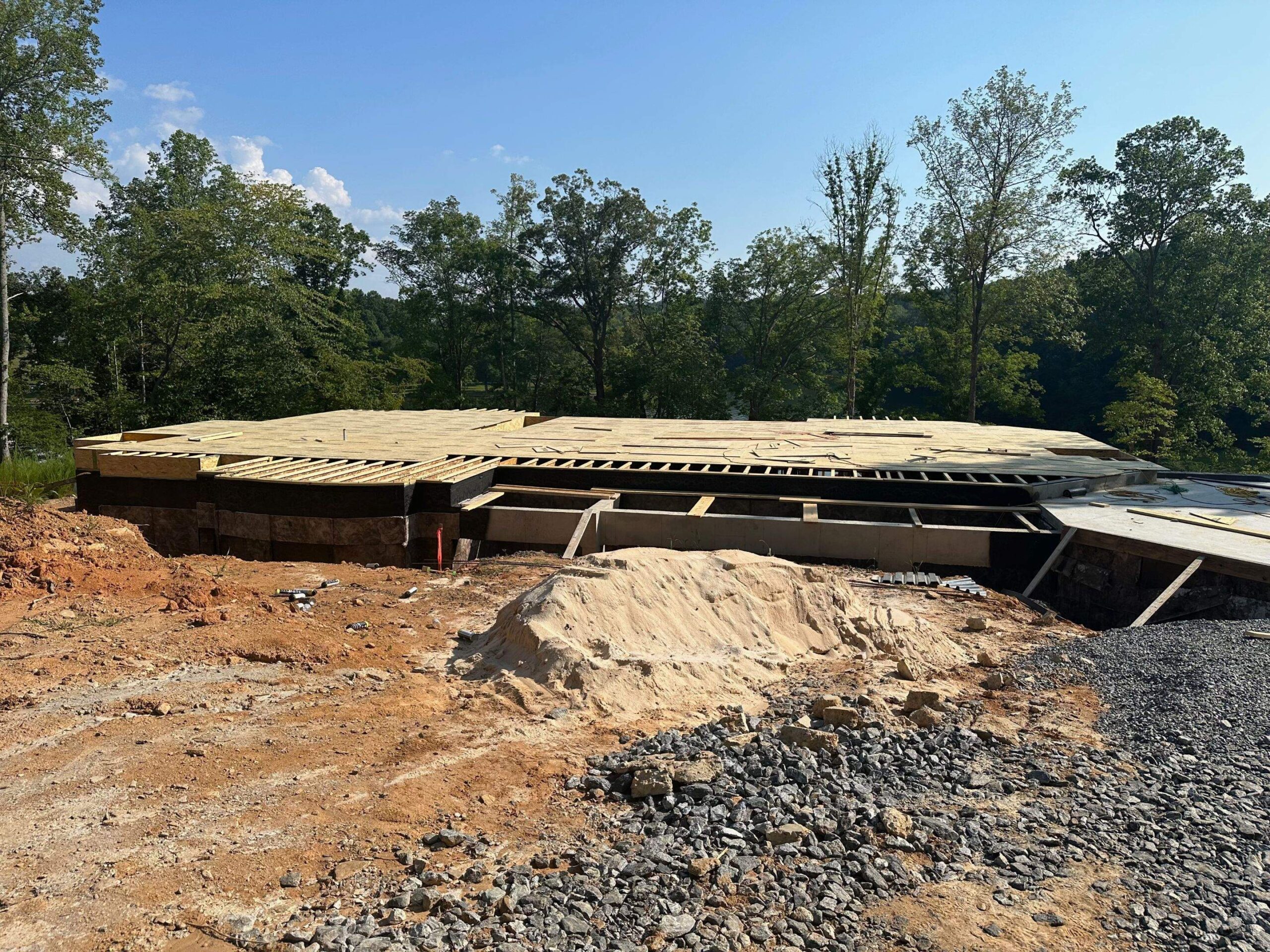 construction of a home foundation with wooden floor joists supporting the structure on a prepared lot surrounded by trees