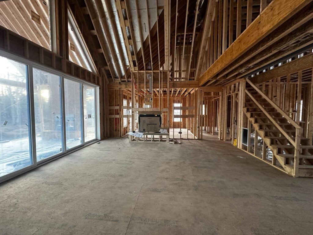 the image shows the framing stage of a custom home construction with open space and large windows installed