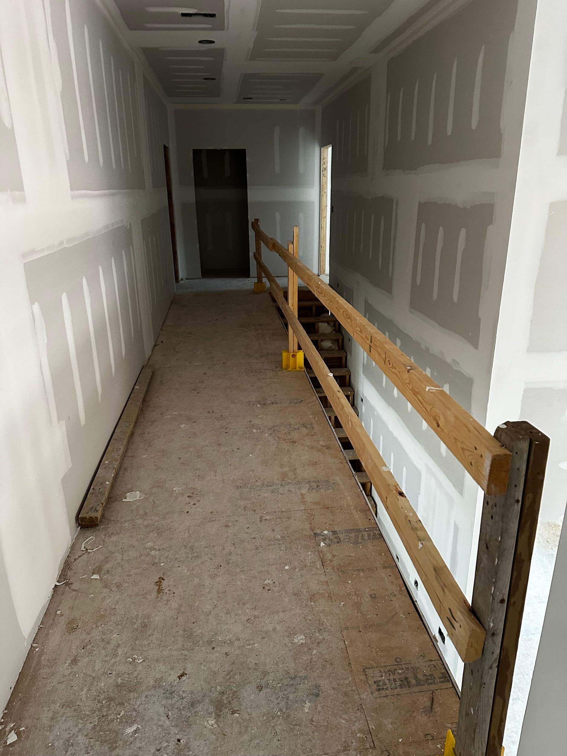 the image shows a future hallway being prepared with drywall and a temporary railing for safety during construction