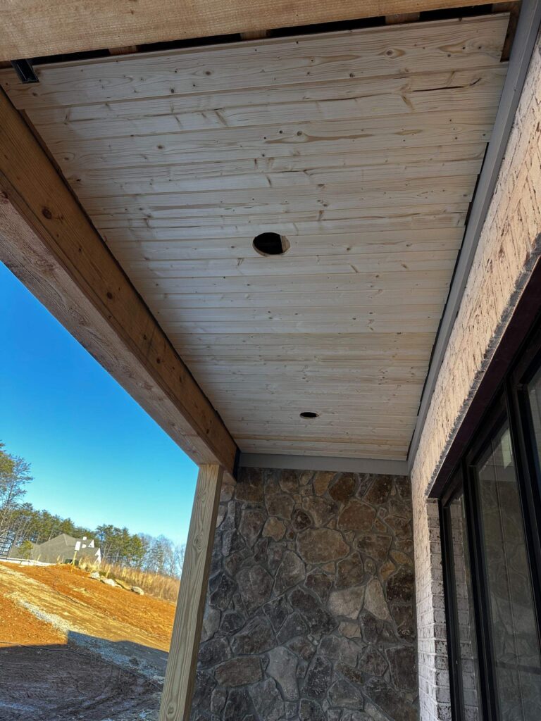 the image shows a partially finished porch ceiling with wood paneling and recessed light fixtures being installed